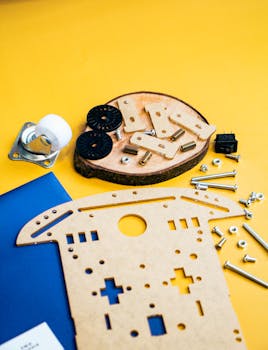 A flat lay of robotics kit parts on a vibrant yellow backdrop, perfect for tech enthusiasts.