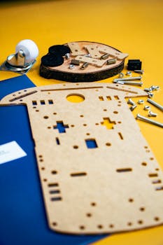 Flat lay of robotics kit components on a bright yellow surface showcasing assembly parts.