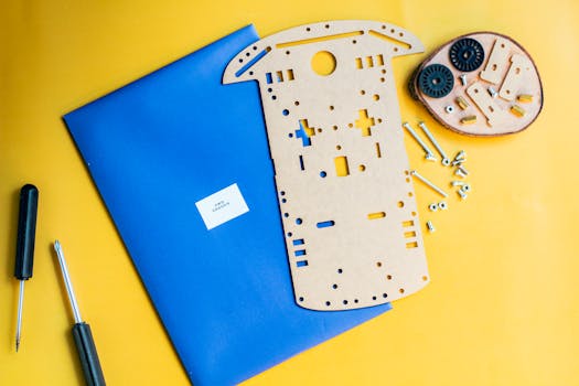 Flat lay of a robotics kit with tools on a vibrant yellow surface, ideal for hobbyists.