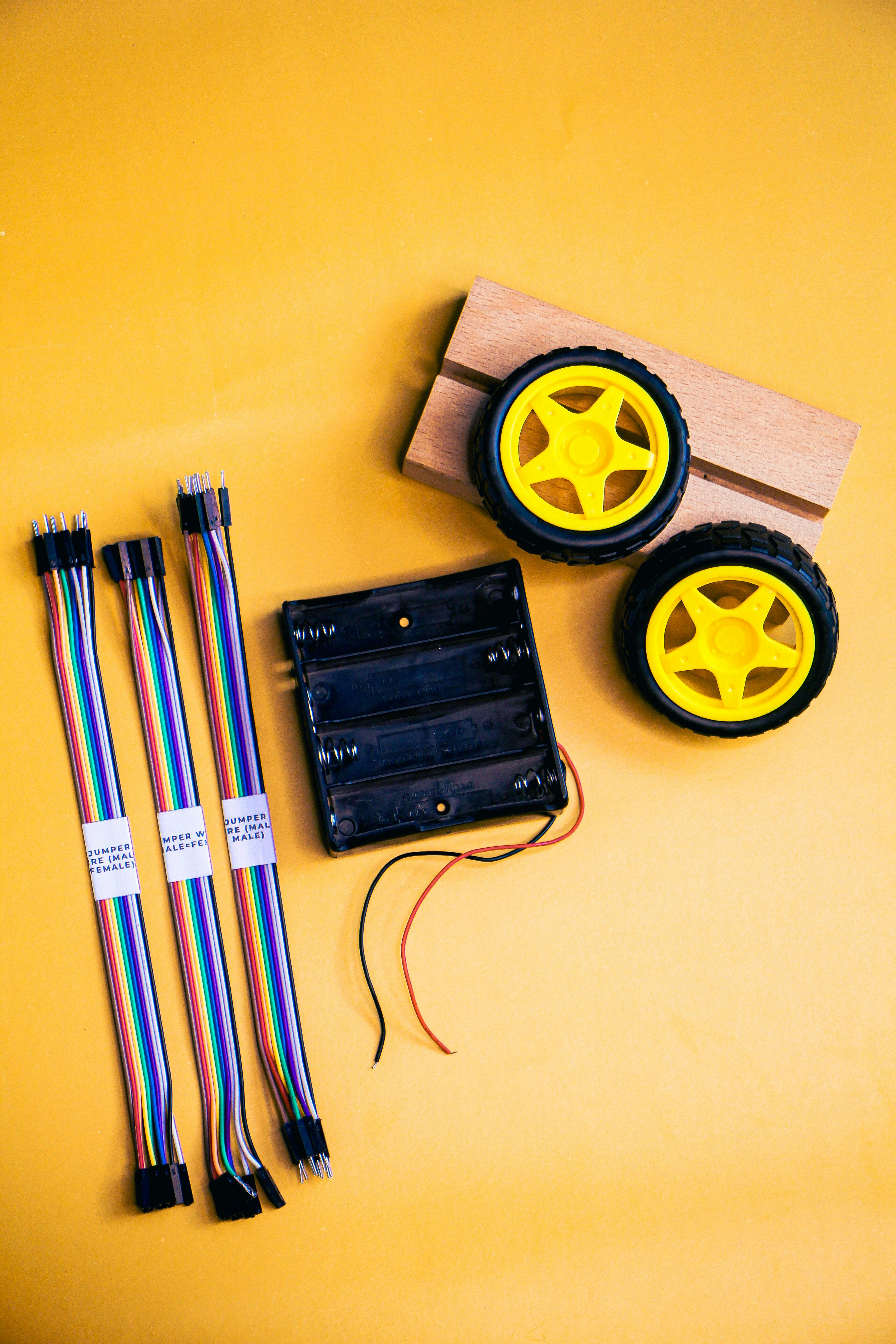 Flat lay of robotics kit components including wheels, wires, and battery pack.