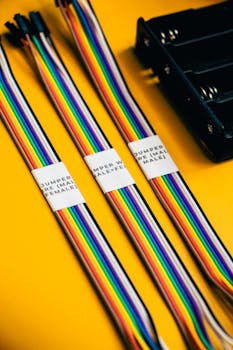Vibrant jumper wires on a yellow background, ideal for robotics and electronics innovation.