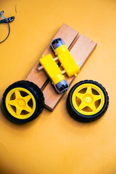 Close-up of a robotics kit with yellow wheels and motors on a vibrant yellow background.