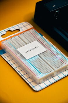 Close-up of an electronics breadboard packaging on a vibrant yellow surface, ideal for tech projects.