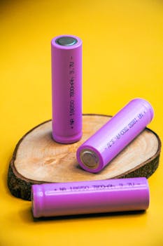 Three vibrant purple batteries displayed creatively on a wooden slice.