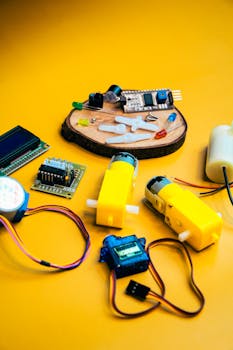 Assorted robotics kit components displayed against a bright yellow background, highlighting innovation and technology.