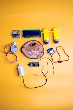 A colorful flat lay of robotics components on a vibrant yellow surface, ideal for tech enthusiasts.