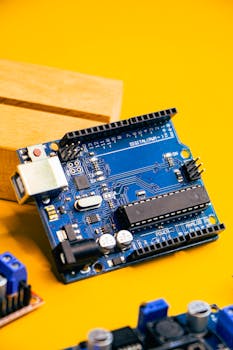 Close-up of an Arduino microcontroller on a vibrant yellow background, showcasing electronic innovation.