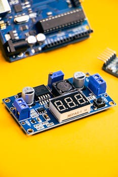 Close-up of an electronic circuit board with digital display on a vibrant yellow background.