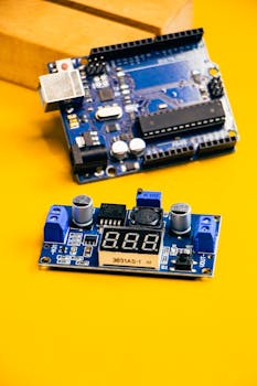 Close-up of an Arduino circuit board and sensor module on a bright yellow background.