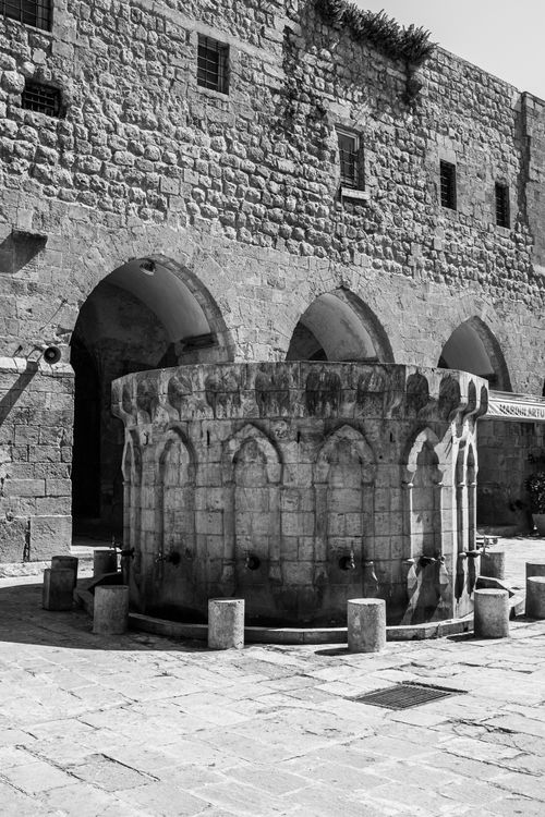 Free Black and white photo of an ancient stone fountain with arches and intricate details. Stock Photo