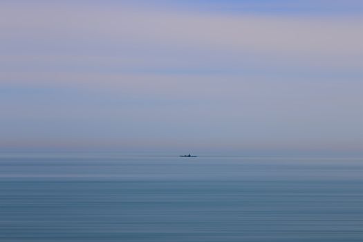 Tranquil scene of a lone kayaker on the calm sea near Hastings under a pastel sky.