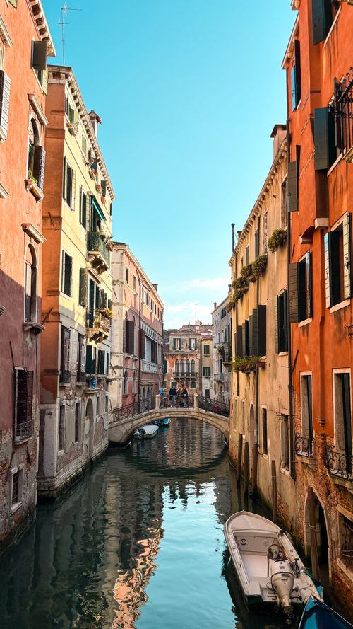 Free Charming Venice canal scene with colorful historic architecture and reflections under a clear sky. Stock Photo