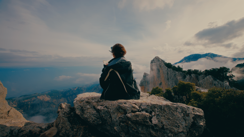 Free Person sitting on mountain rock enjoying the view at dusk. Stock Photo