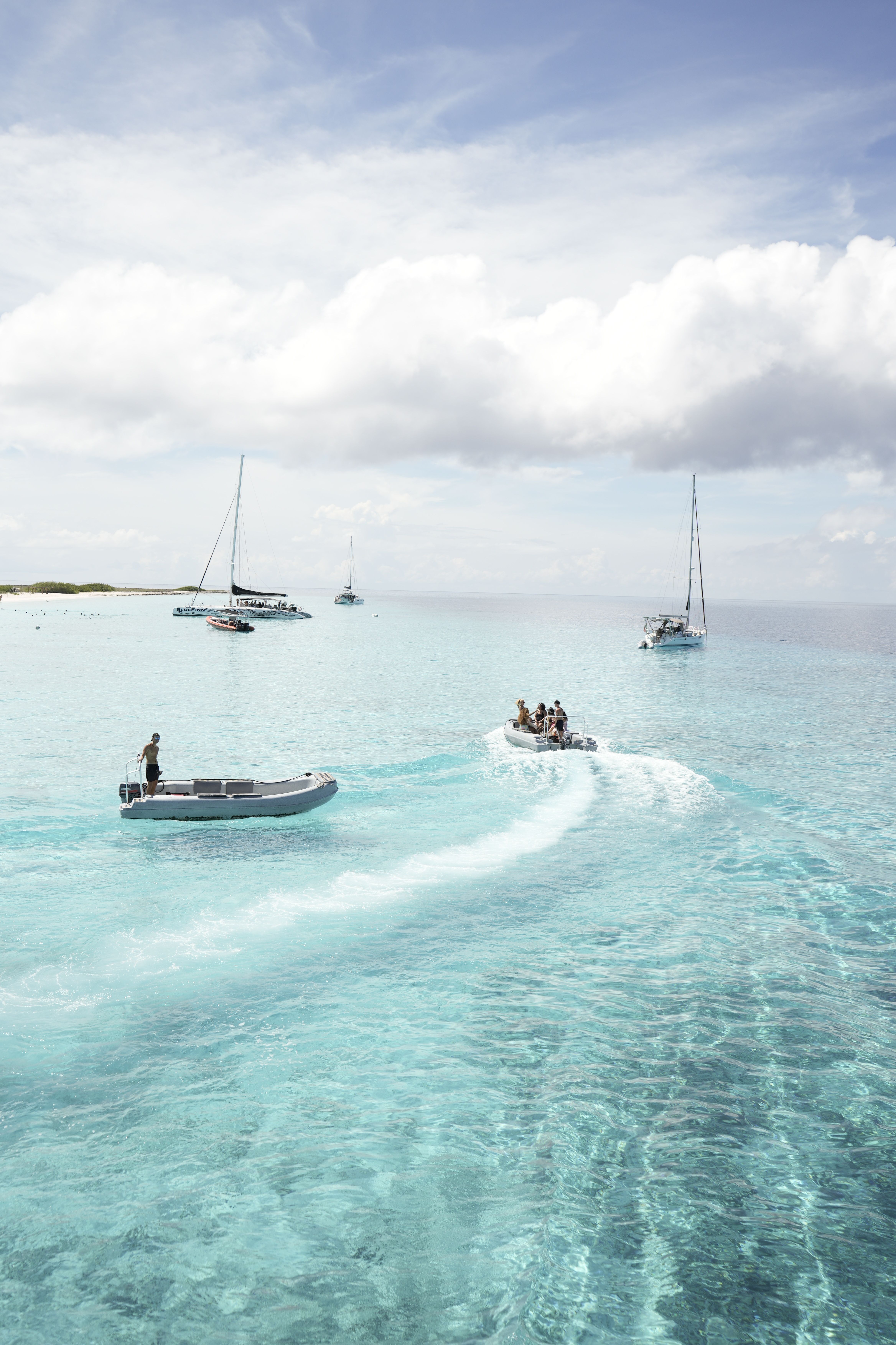 Serene view of boats sailing over turquoise waters under a blue sky.