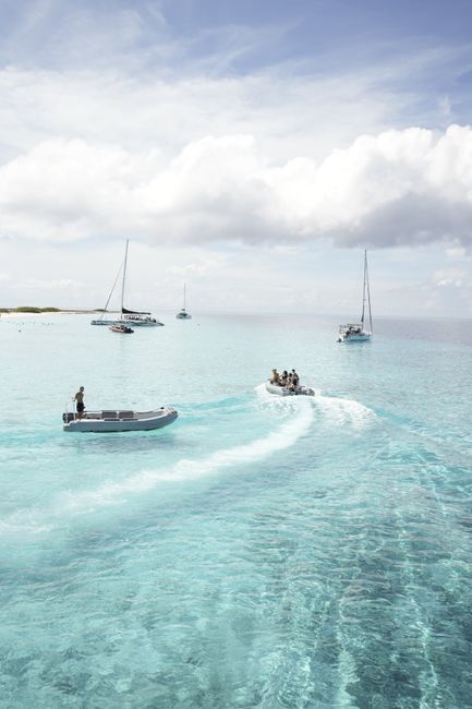 Serene view of boats sailing over turquoise waters under a blue sky.