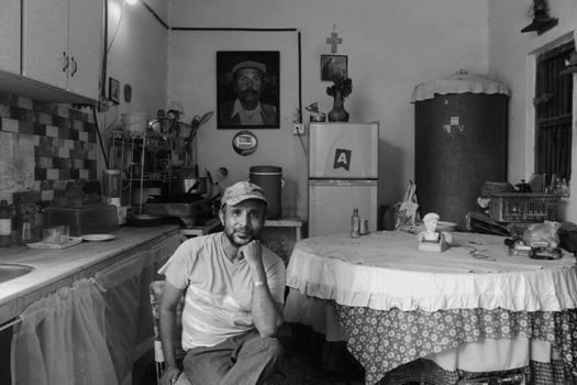 A contemplative man in a rustic kitchen setting, Faisalabad, Pakistan.