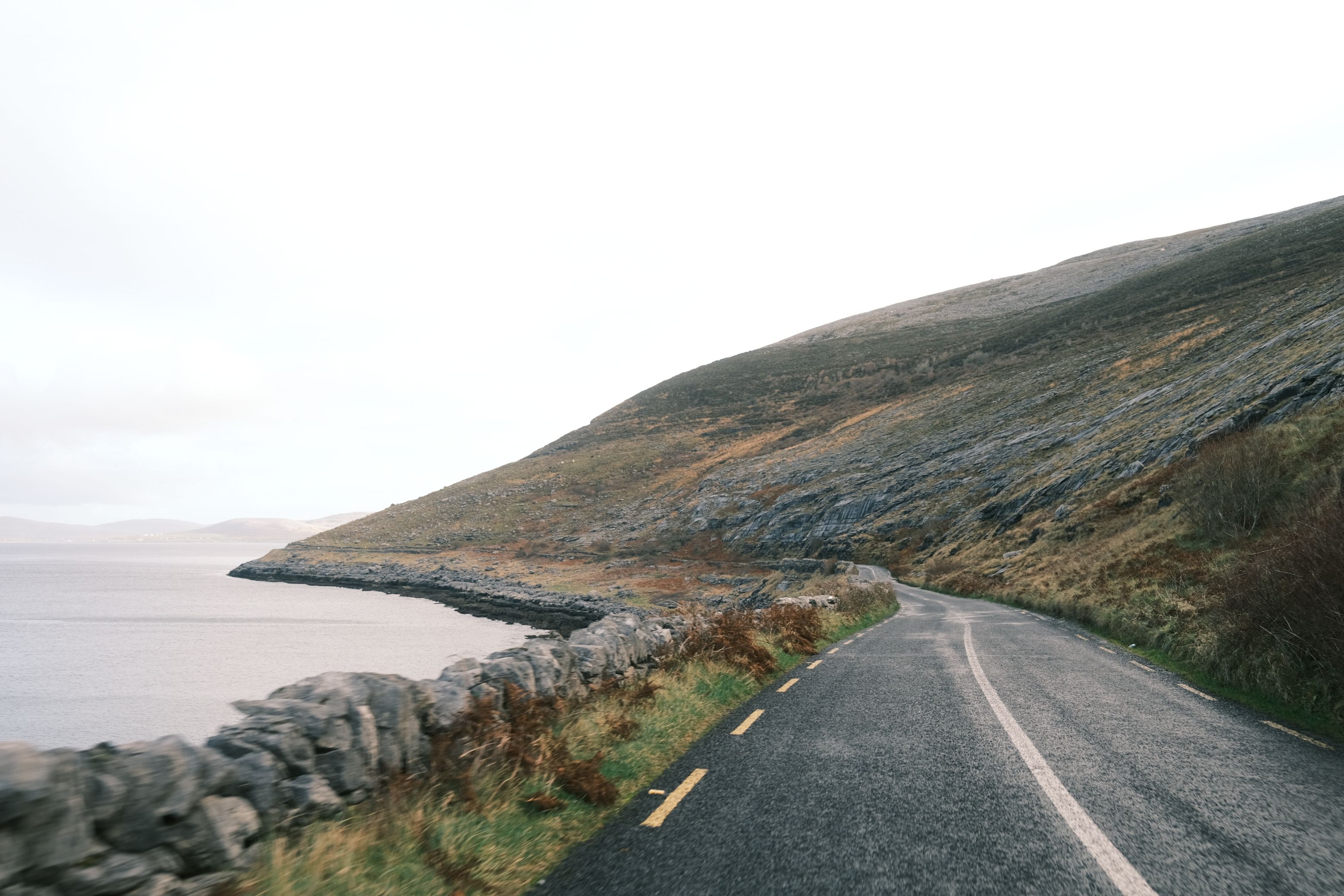 Picturesque coastal road along a rocky hillside by the ocean, ideal for travel imagery.