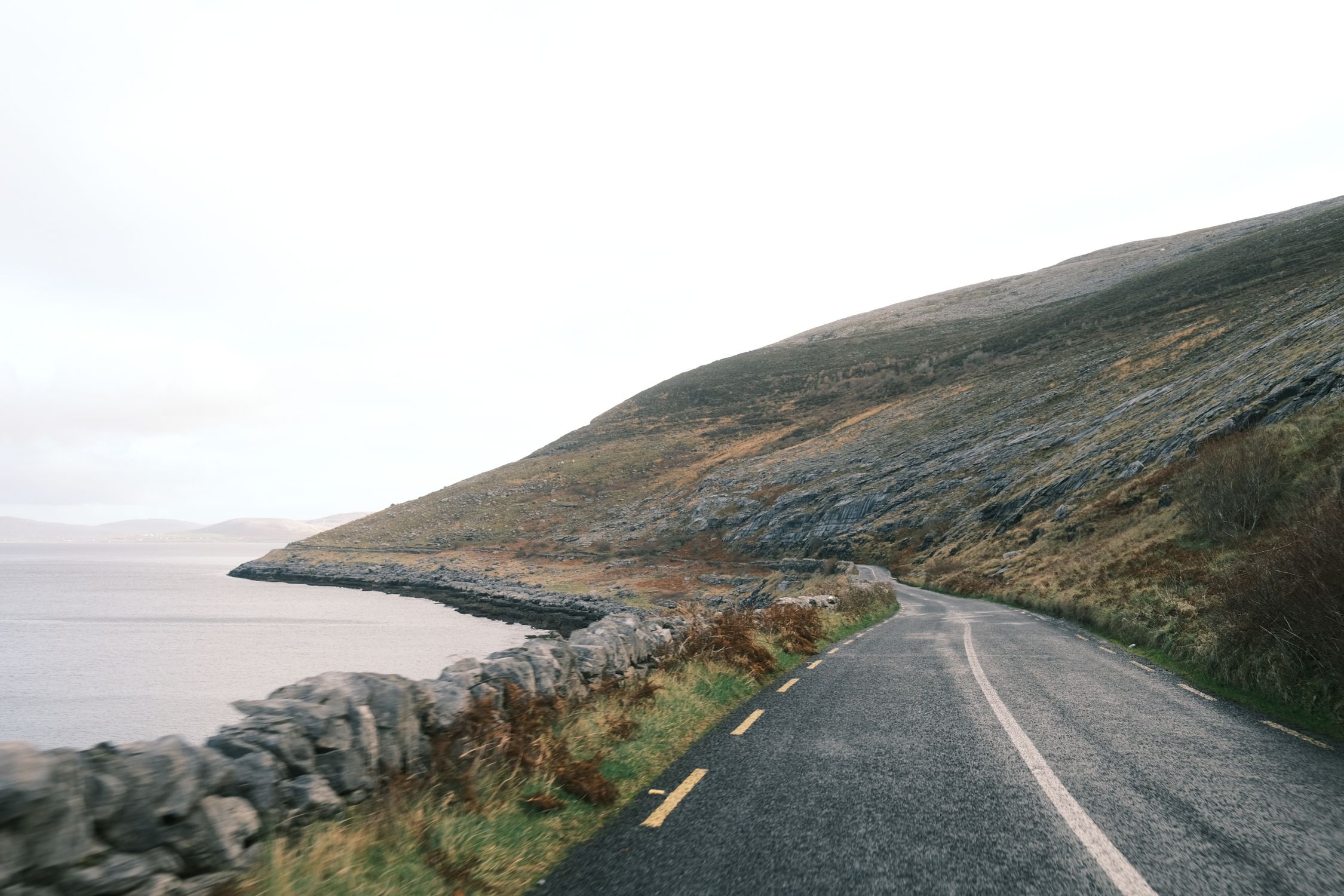 Picturesque coastal road along a rocky hillside by the ocean, ideal for travel imagery.