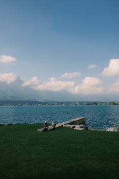 Peaceful scene of two people relaxing by a lake with mountain views.