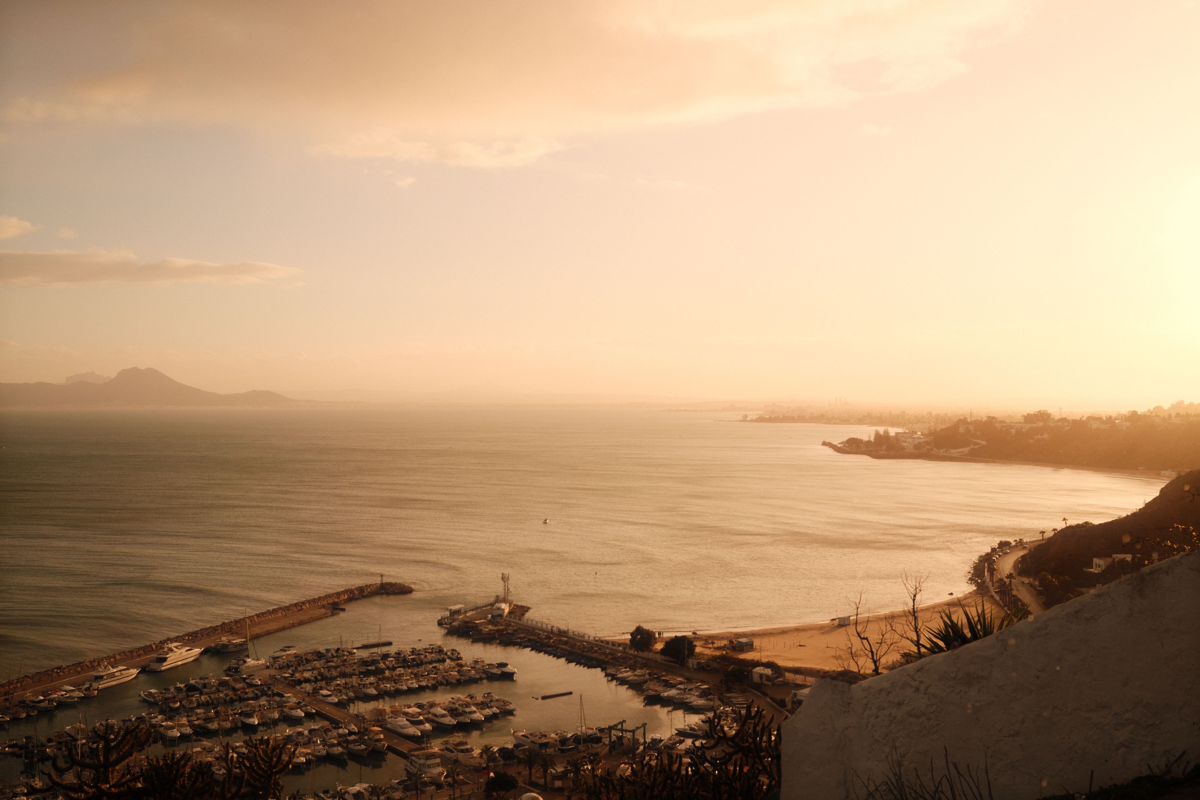 A warm sunset casting golden hues over Carthage Harbor in Tunis, Tunisia, offering a serene coastal view.