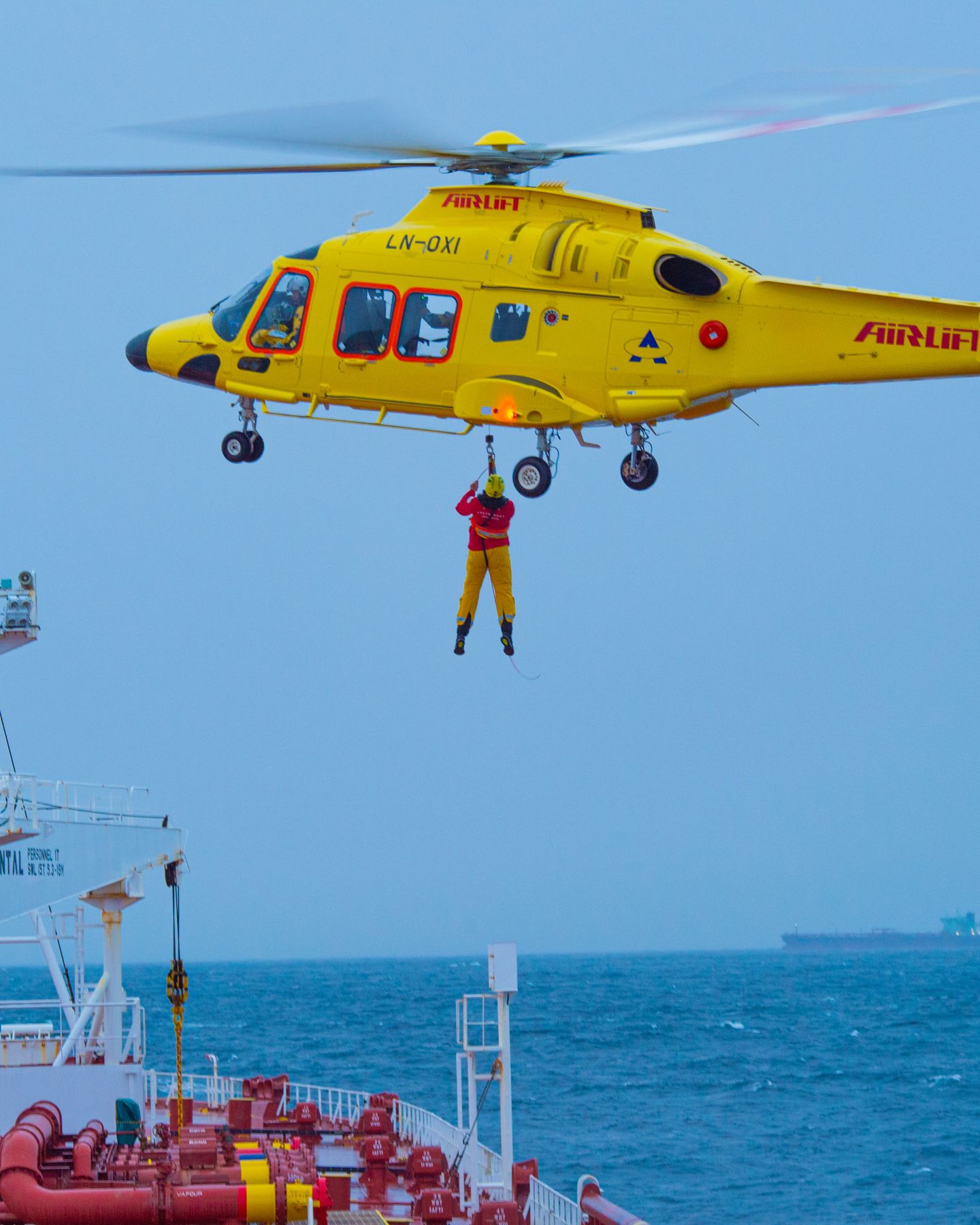Maritime rescue paramedic deploying on a line over the sea