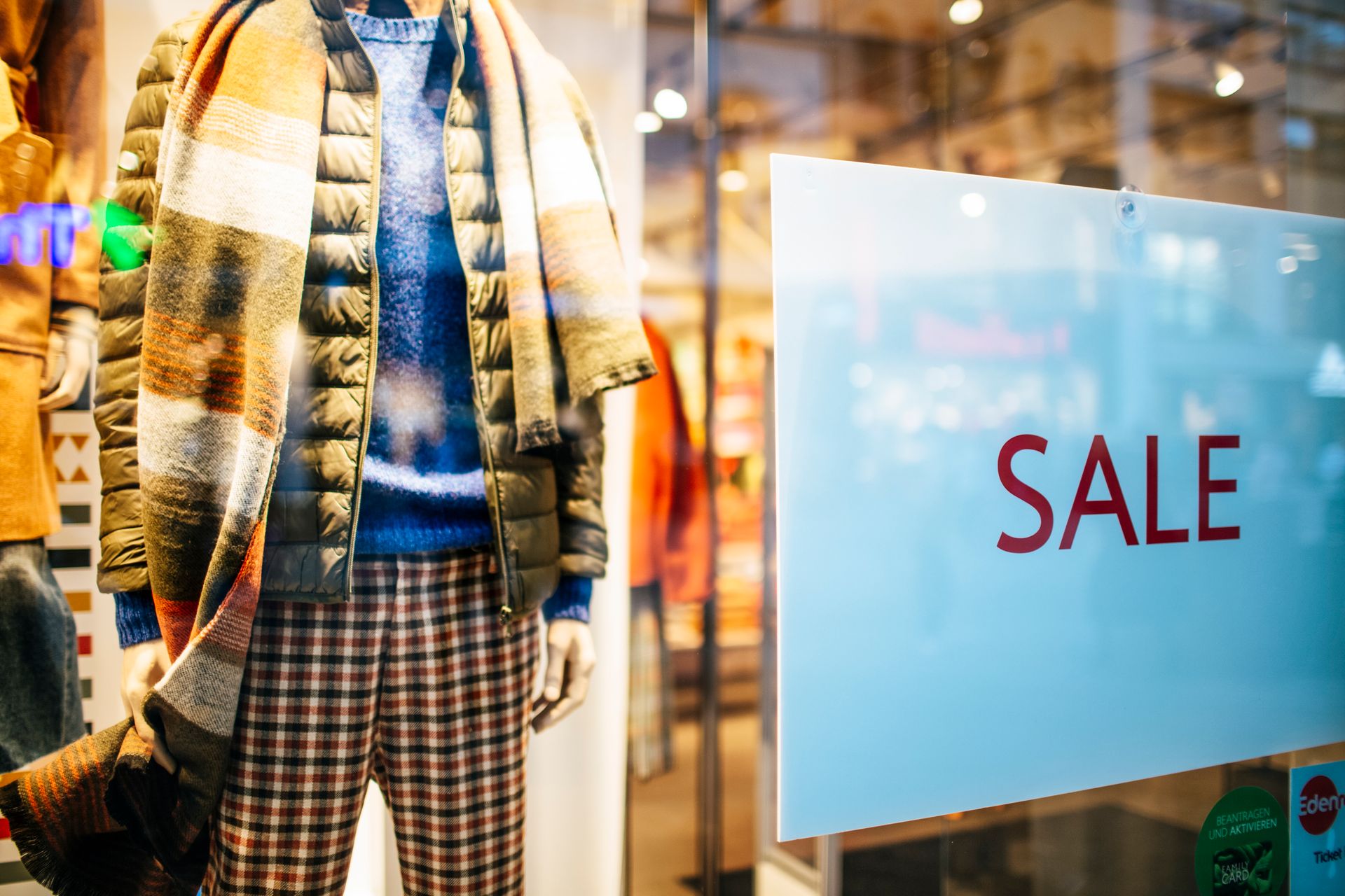 Mannequin display of winter fashion with sale sign in a clothing store window.