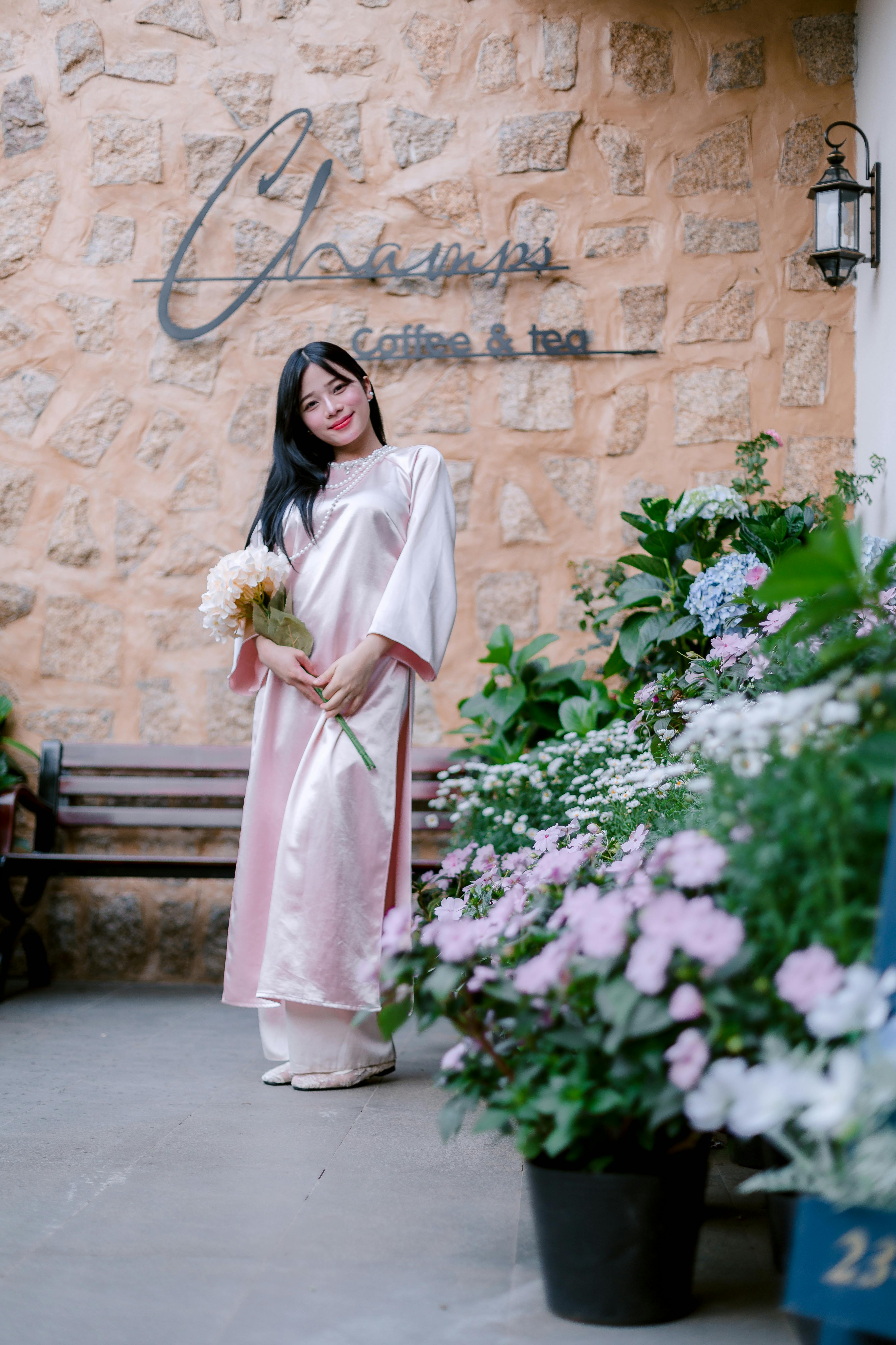 Woman in pink traditional dress with flowers outside a cafe.