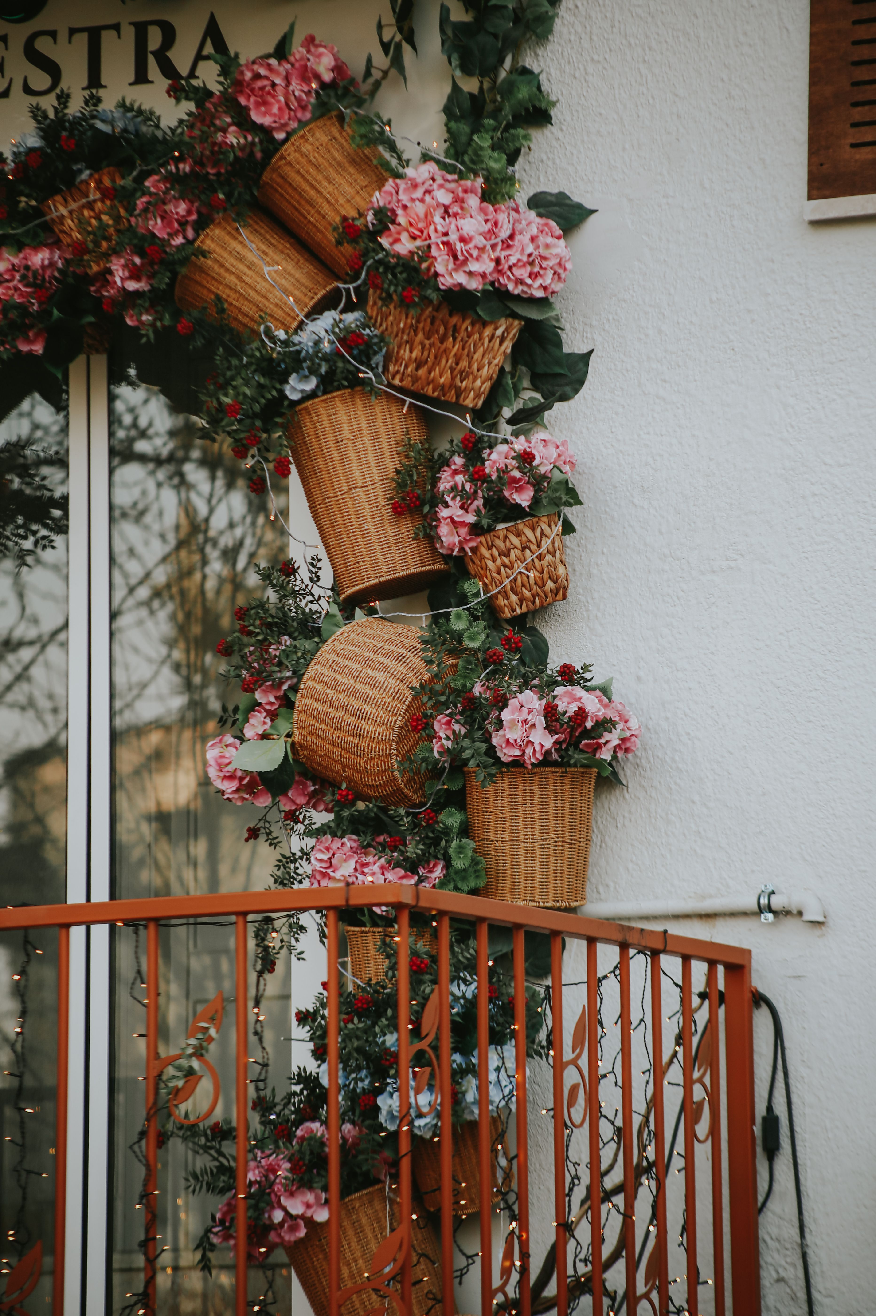 Wall-mounted baskets with pink flowers decorating an outdoor balcony wall