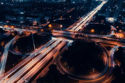 A vibrant aerial shot of city roads with light trails at night, showcasing urban energy.