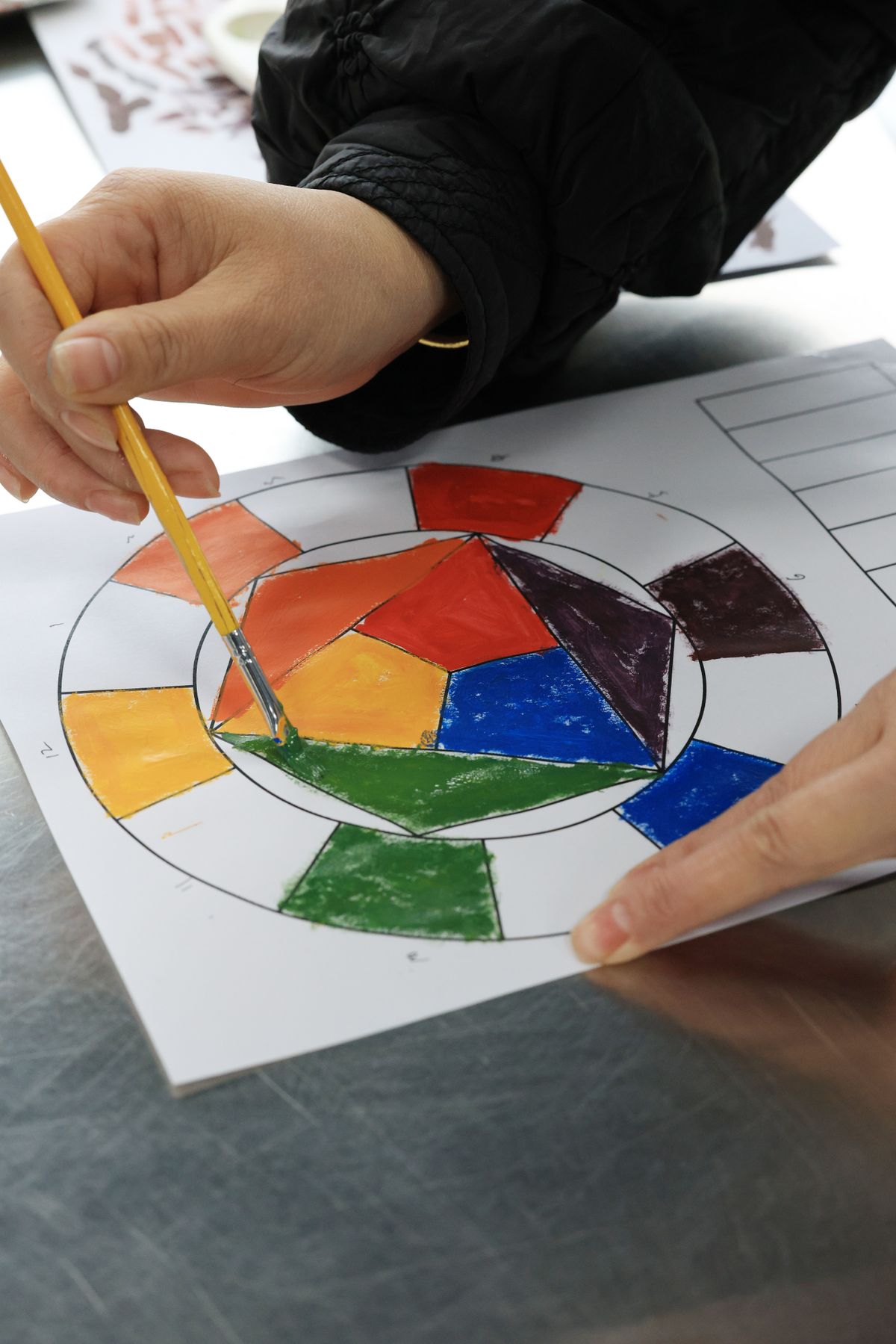Manos coloreando un diseño geométrico circular