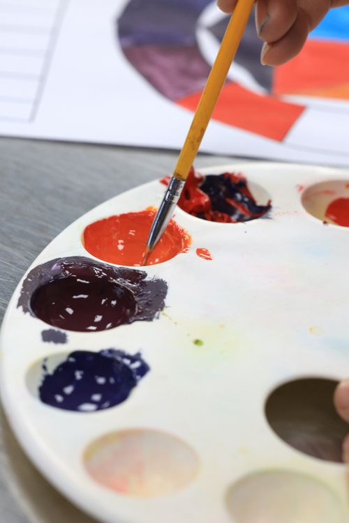 Free Close-up of a paint palette with vibrant colors and brush in action, capturing an artistic moment. Stock Photo
