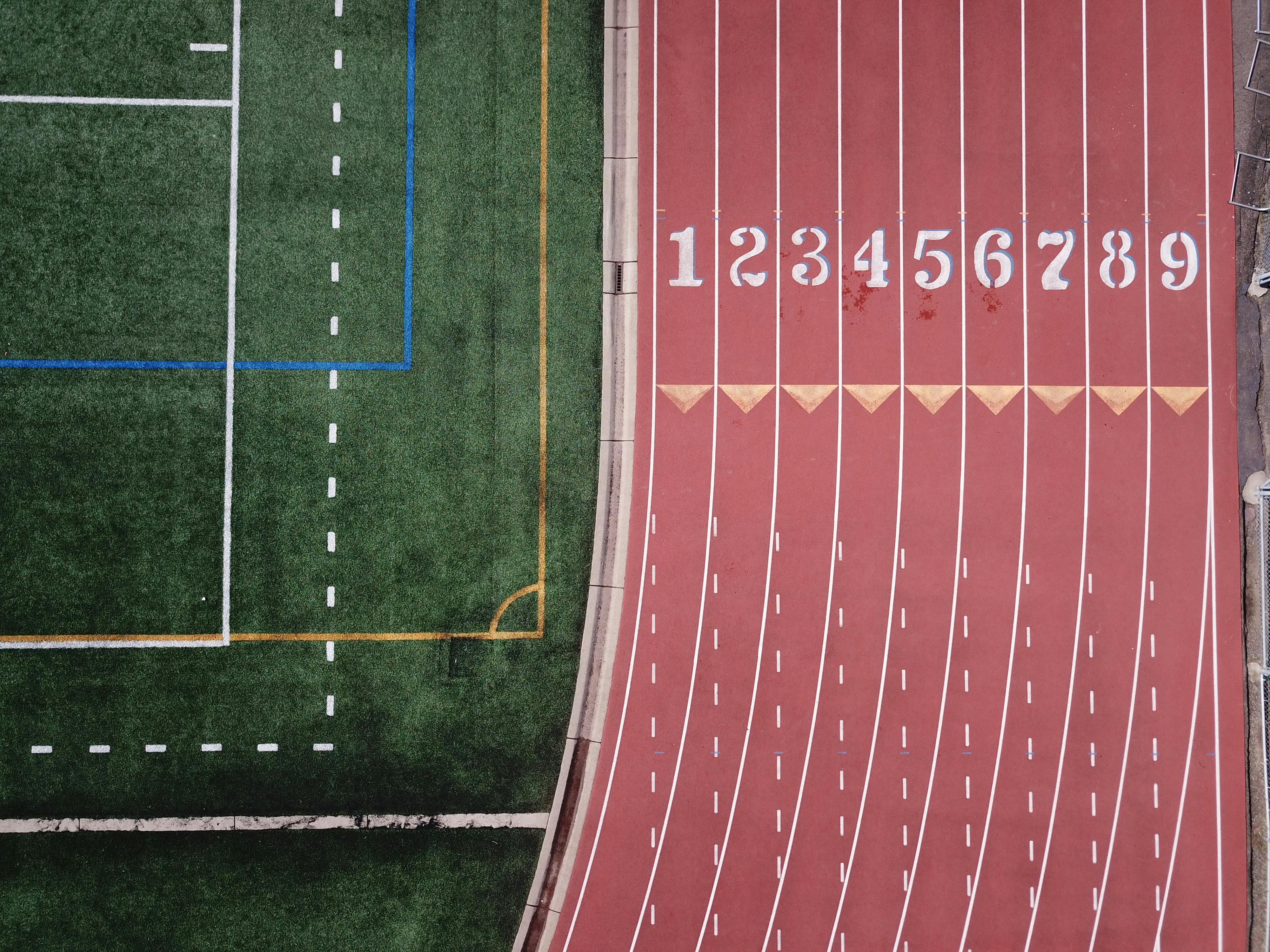 Aerial shot of a track field with numbered lanes and adjacent football area.