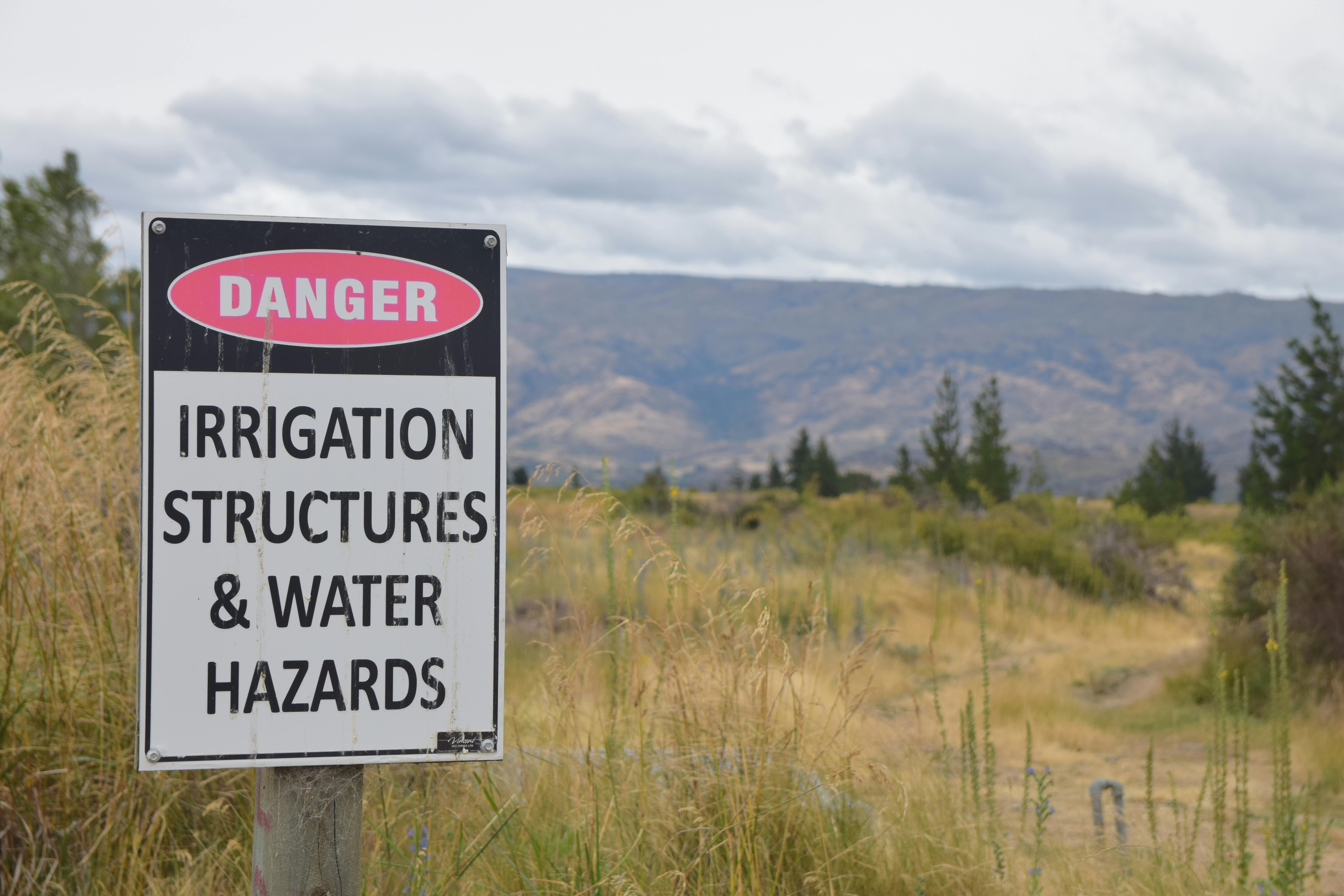 Danger sign warning about irrigation structures and water hazards in rural Otago, New Zealand.