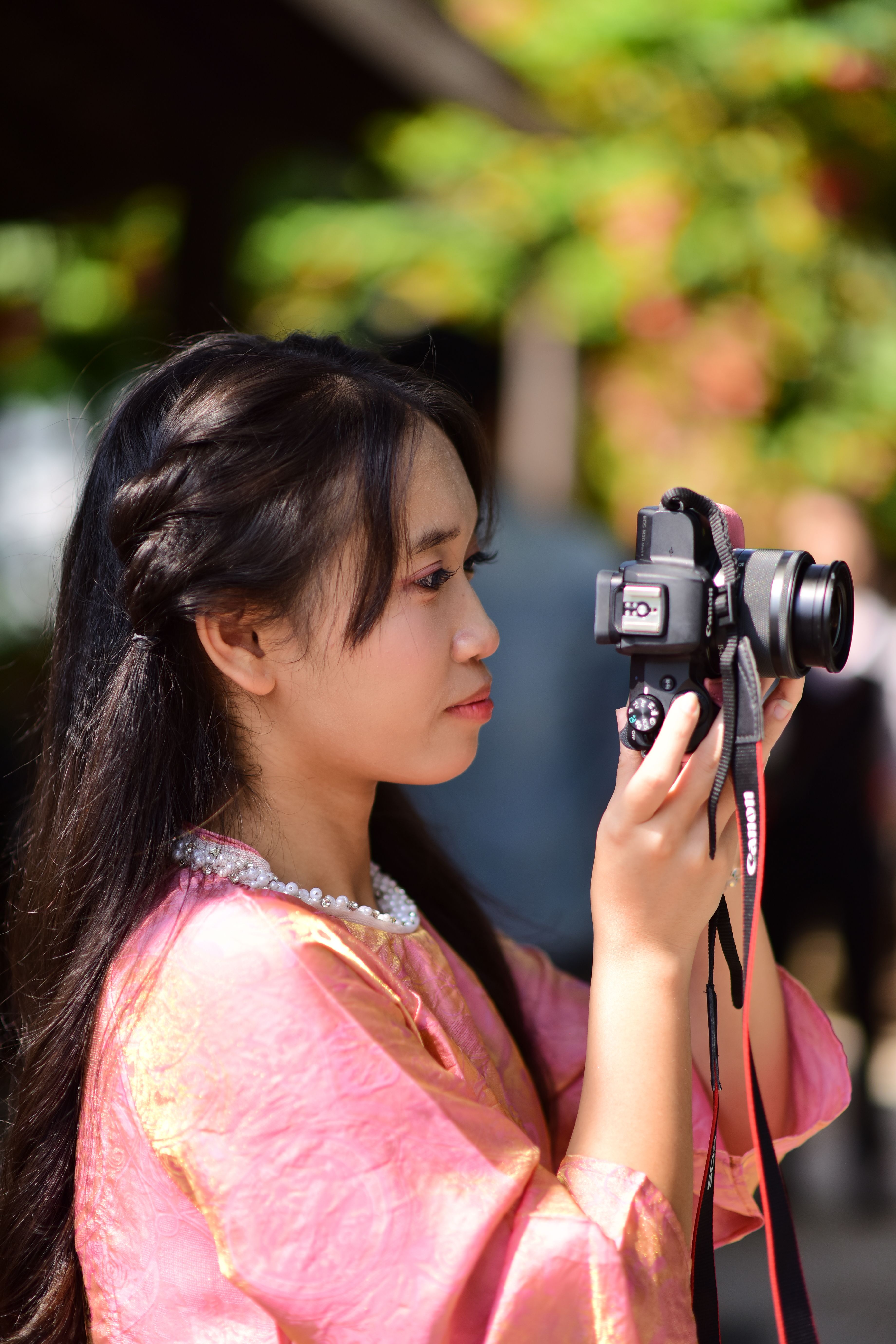 Young Woman in Traditional Dress Photographing Outdoors · Free Stock Photo