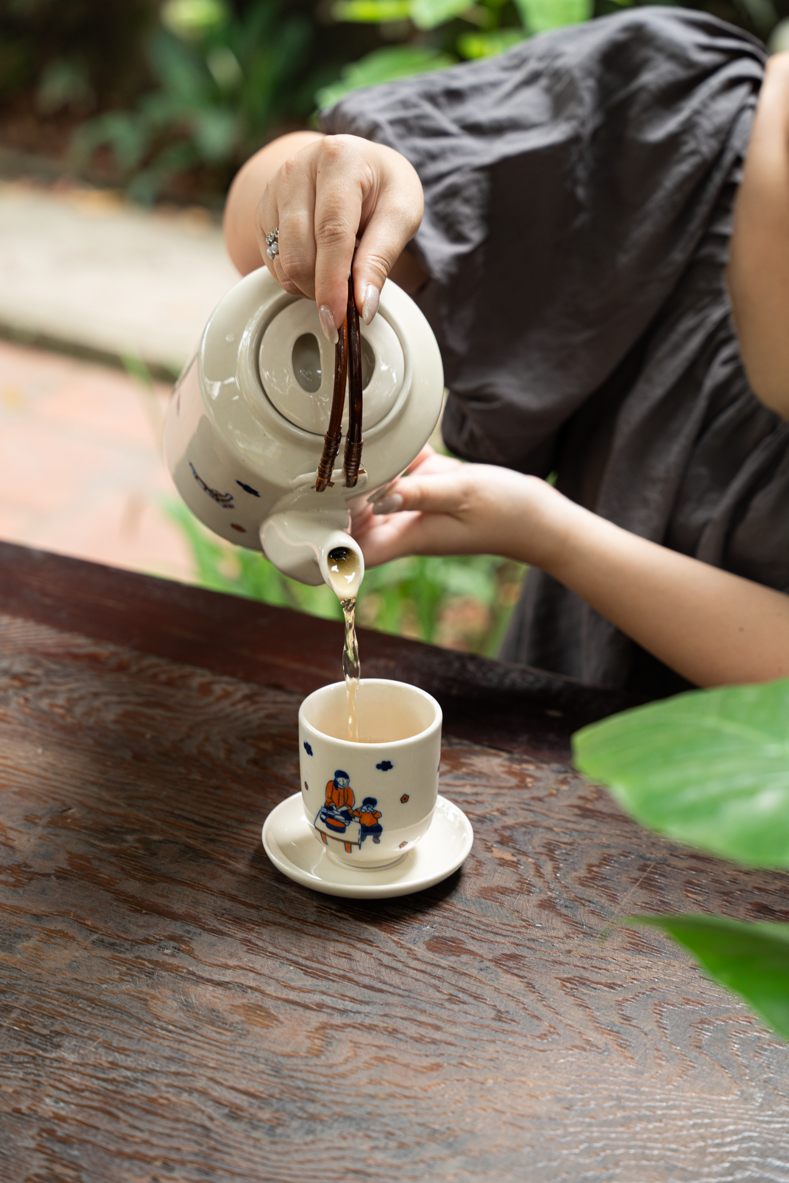 A person pours tea into a ceramic cup, creating a cozy and relaxing atmosphere outdoors.