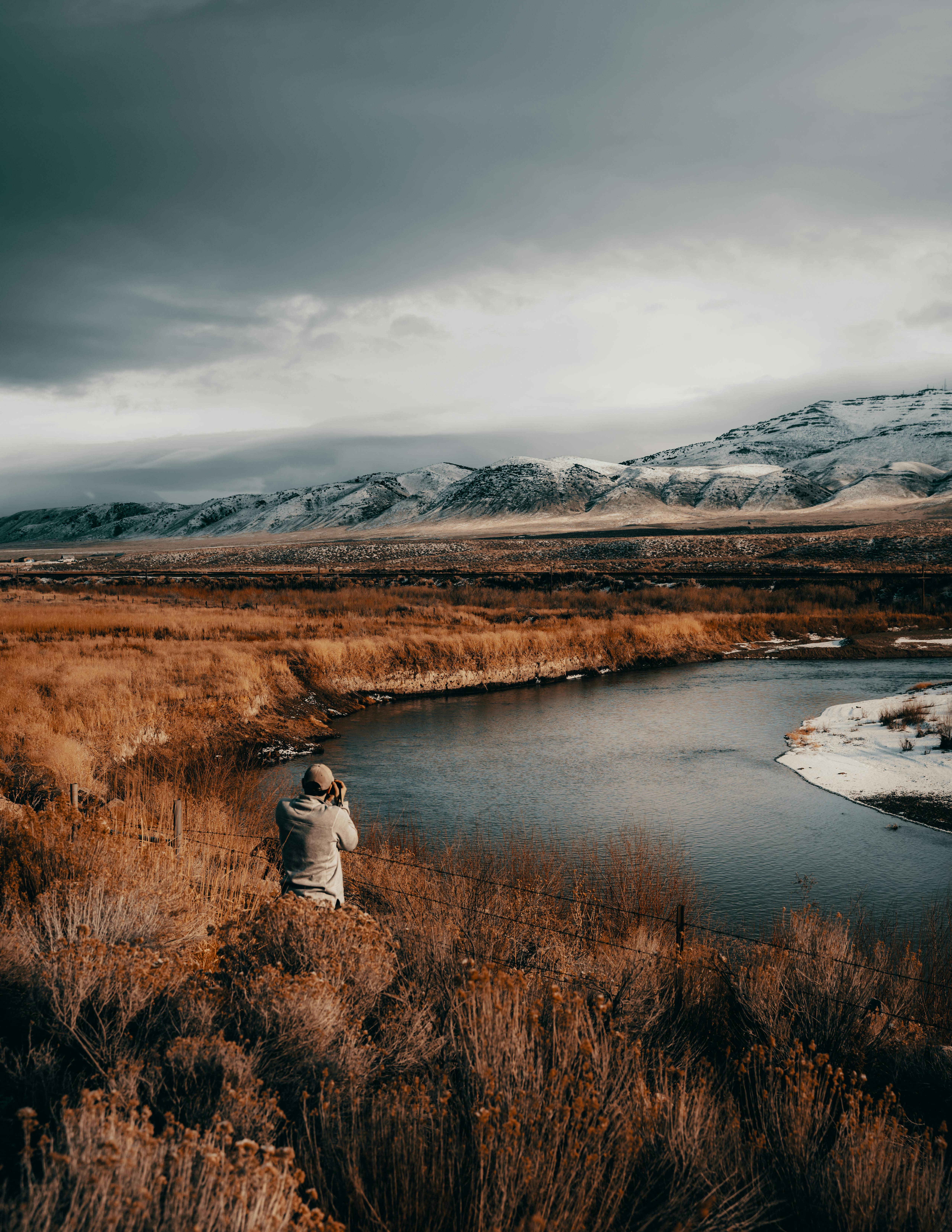 man in front of body of water under cloudy sky