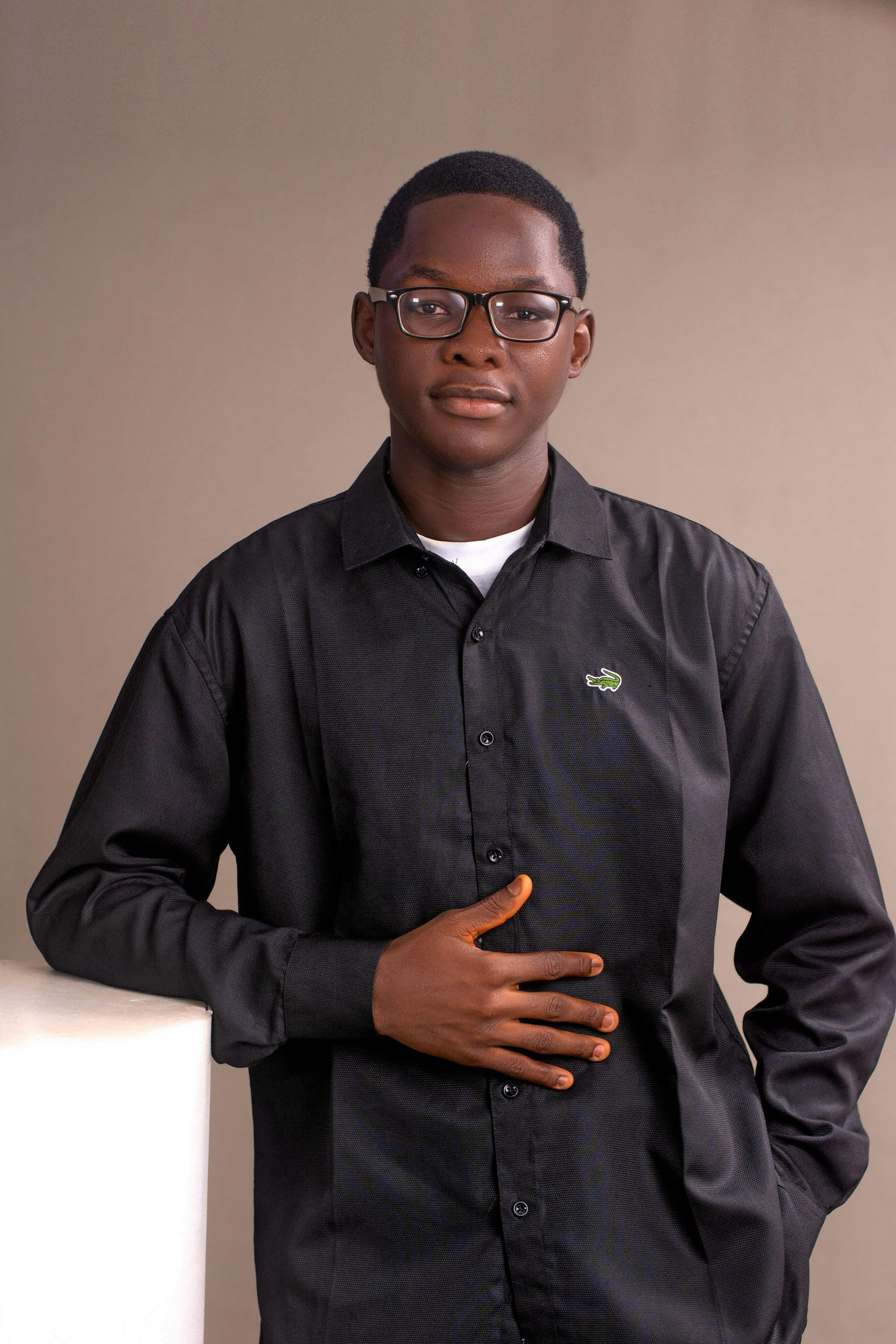 Portrait of a confident young man in a black shirt, posing indoors with a neutral expression.