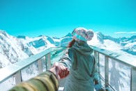 一名穿着冬装的妇女牵着孩子的手，走在泽尔湖畔风景优美、白雪皑皑的山顶甲板上