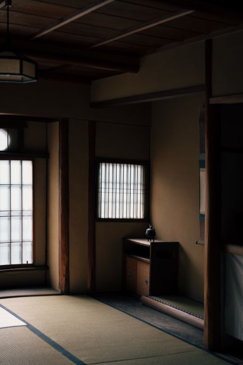 Free Dimly lit traditional Japanese room featuring tatami mats and shoji screens, creating a serene atmosphere. Stock Photo