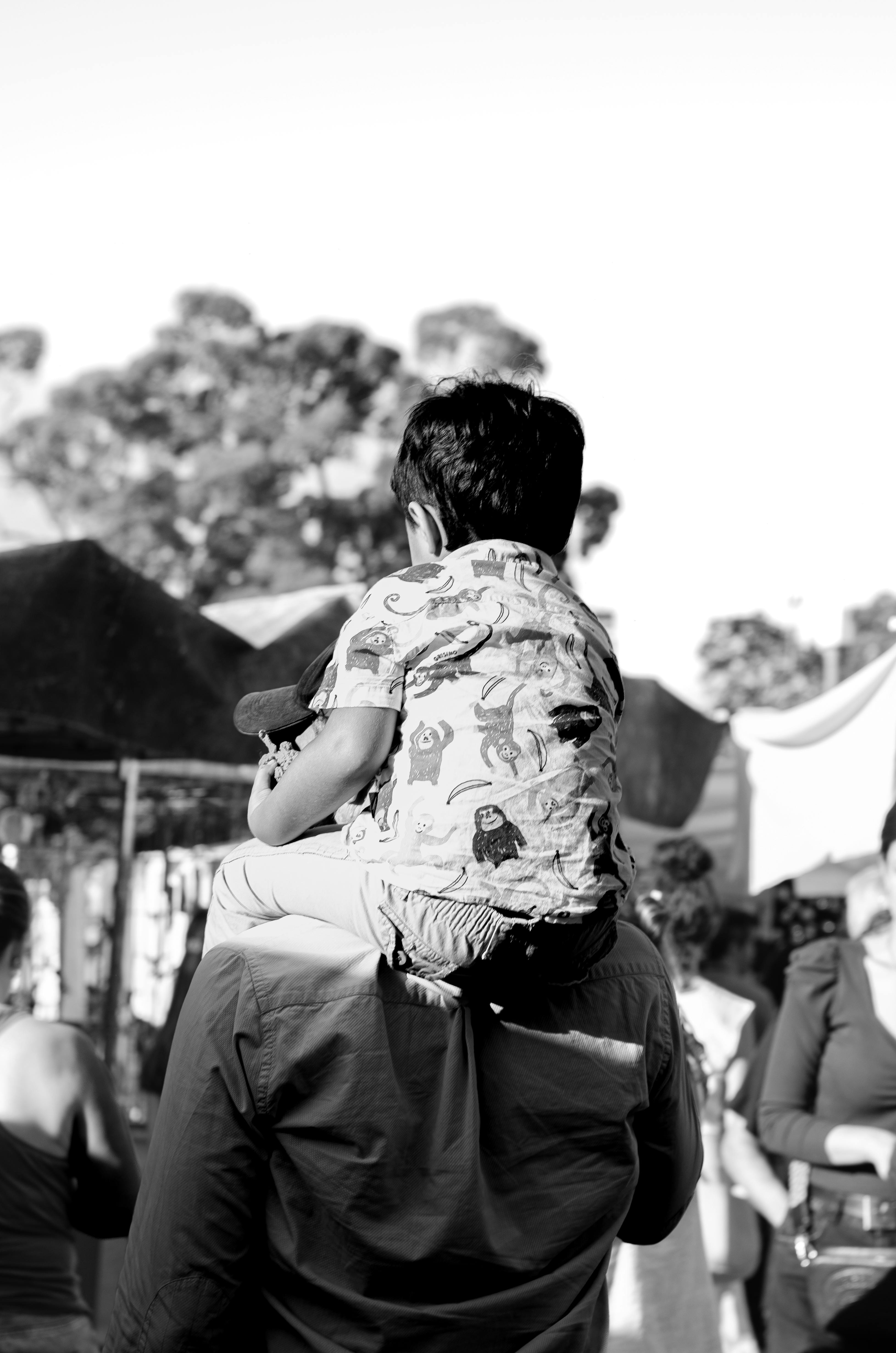 Zadarmo Dojímavý čiernobiely moment otca nesúceho syna na pleciach na festivale pod holým nebom. Fotka z fotobanky