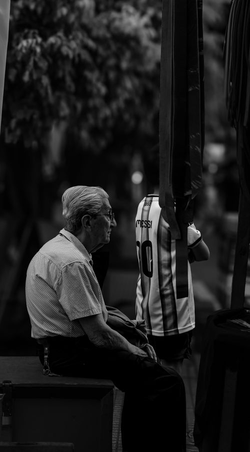 Free Formal street shot capturing an elderly man sitting outdoors in monochrome. Stock Photo