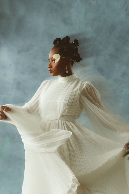 Graceful portrait of a woman in a flowing white dress against a soft backdrop.