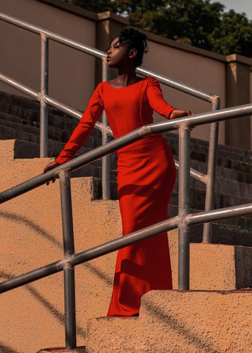 Free A woman in a striking red dress gracefully poses on an outdoor staircase. Stock Photo