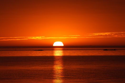 Captivating view of a vivid orange sunset over serene ocean waters, perfect for travel inspiration.