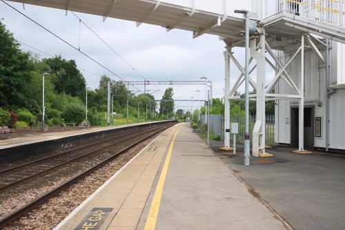 Free Empty railway station platform in Kidsgrove, England with overhead bridge on a cloudy day. Stock Photo