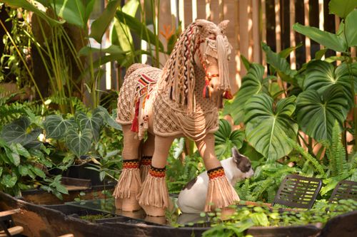 Free A straw horse statue decorates a green tropical garden, adding an artistic touch. Stock Photo