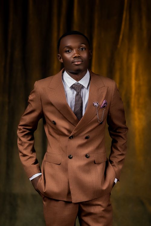 Free Portrait of a young man in a stylish brown suit against a dark background. Stock Photo