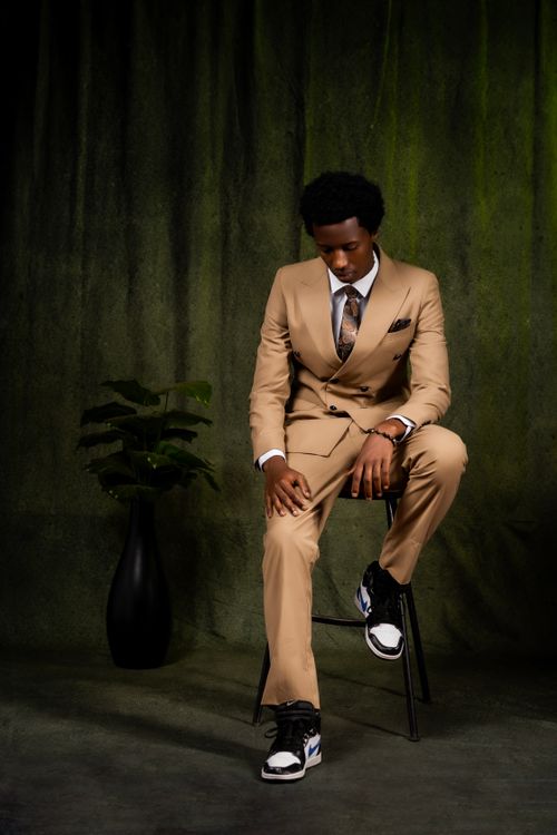 Free A young man in a tan suit poses stylishly indoors with a modern vibe. Stock Photo