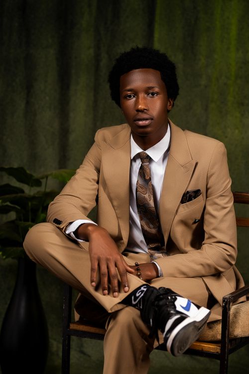 Free Elegant portrait of a man in a tan suit and sneakers sitting indoors. Stock Photo