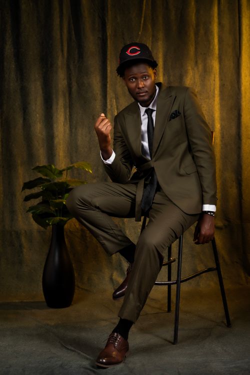 Free A fashionable man in a suit sits confidently on a stool in an indoor setting. Stock Photo